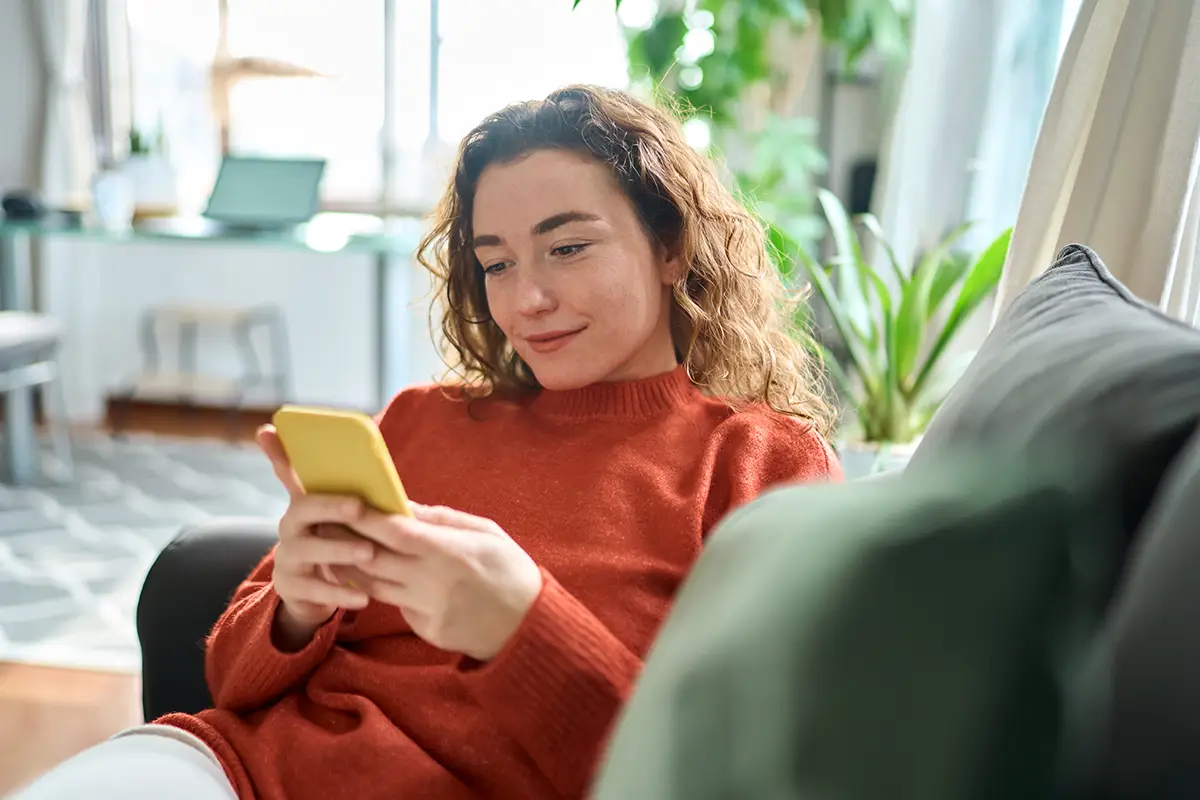 Woman looking at Welly products on her phone while sitting on a couch.